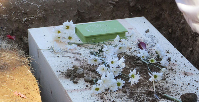 casket covered with flowers and dirt at a burial